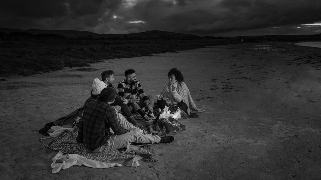 Drinkers enjoy whisky by a bonfire on the beach at Jura