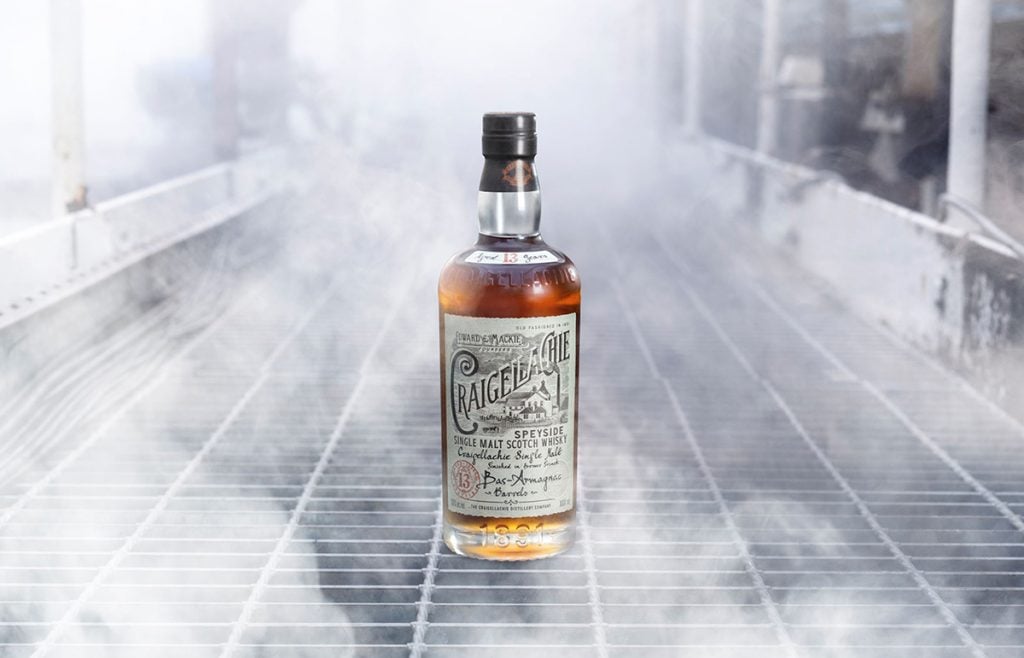 A bottle of Craigellachie 13 Year Old Bas-Armagnac Cask Finish Whisky in a distillery surrouded by smoke