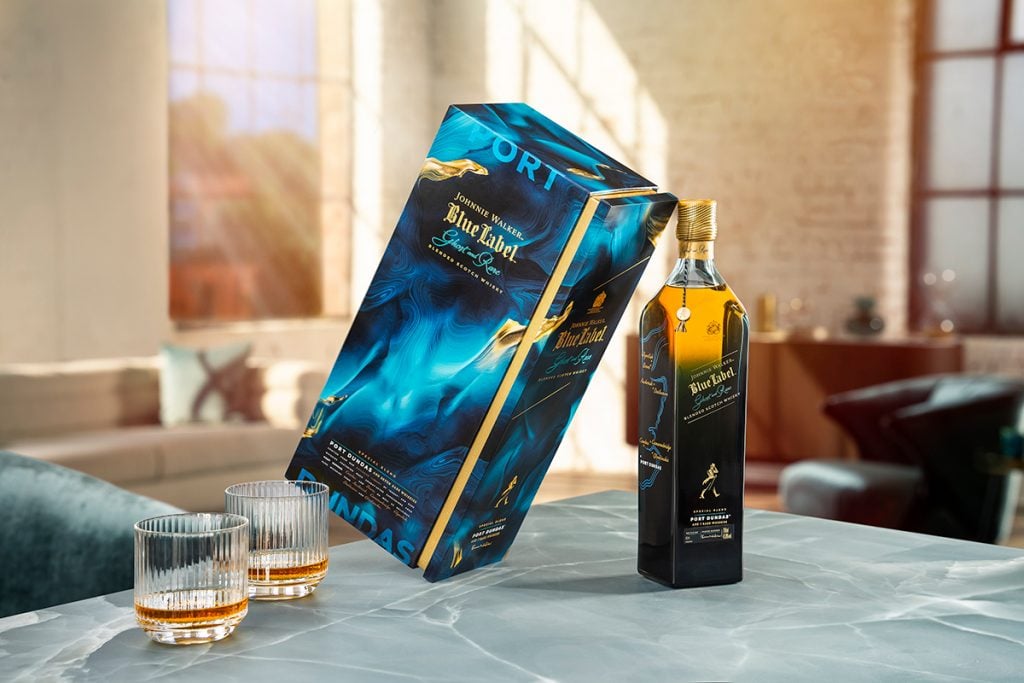 Two glasses of whisky filled with Johnnie Walker Ghost and Rare, next to its bottle and presentation box on a table