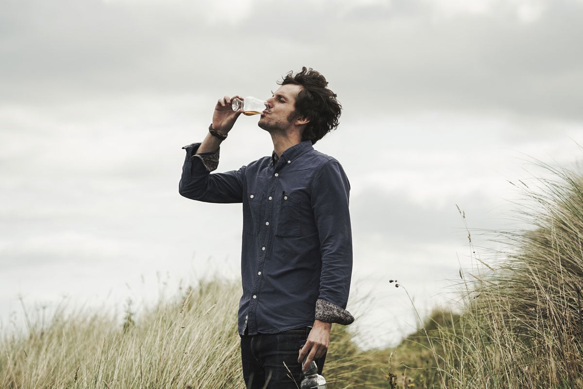 Jake Mountain drinking whisky by the coast