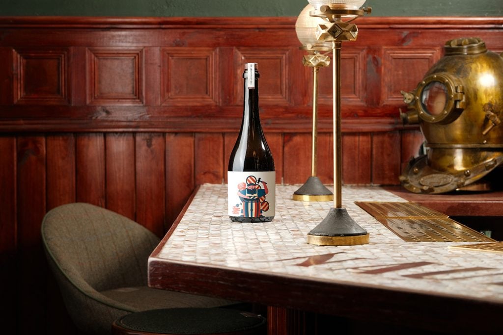 A bottle of Perpetuity whisky on a table next to a lamp