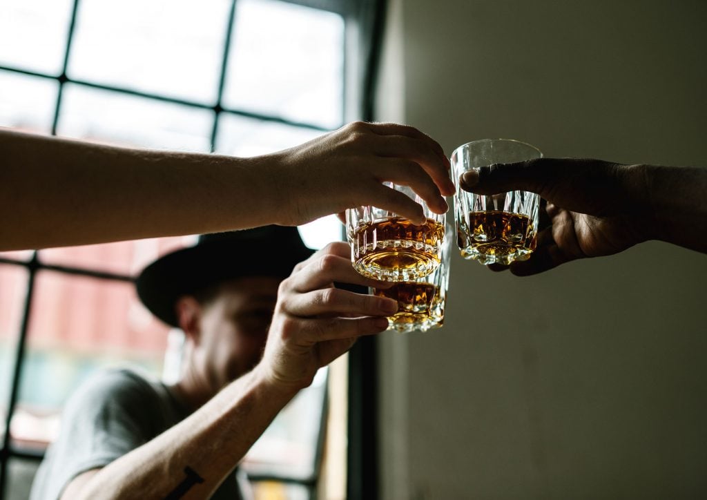 Affordable whisky in glasses raised in cheers by budget-conscious drinkers