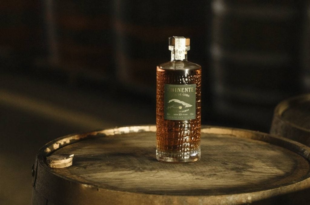 A bottle of Cuban rum Eminente Gran Reserva 10 Year Old on a barrel