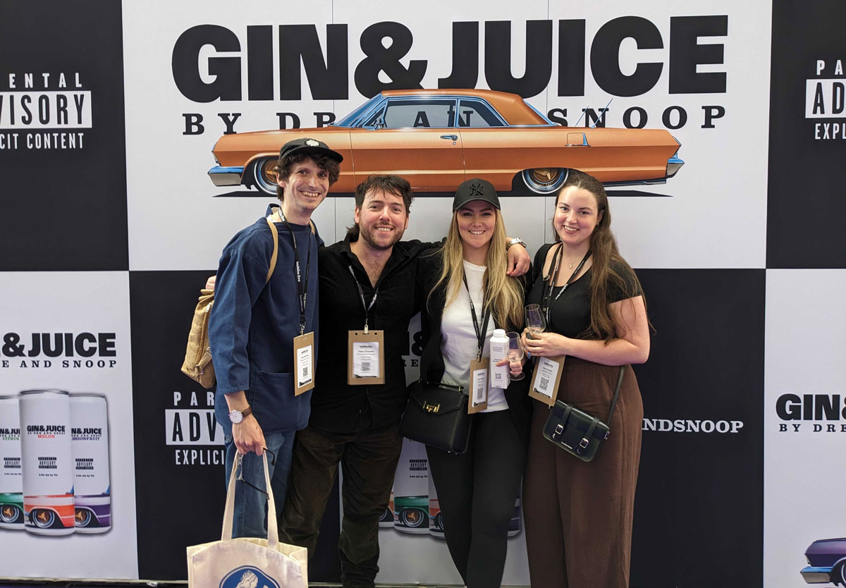 Master of Malt team in front of Gin & Juice promotional wall