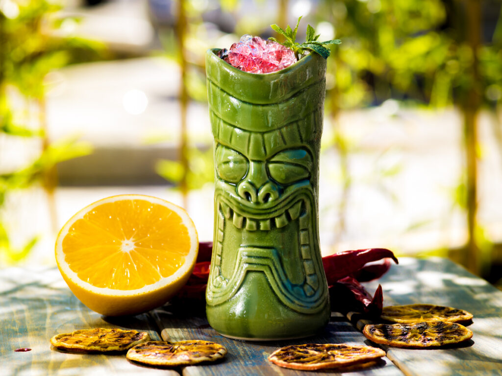 Cocktail in the tiki glass on the wood table.