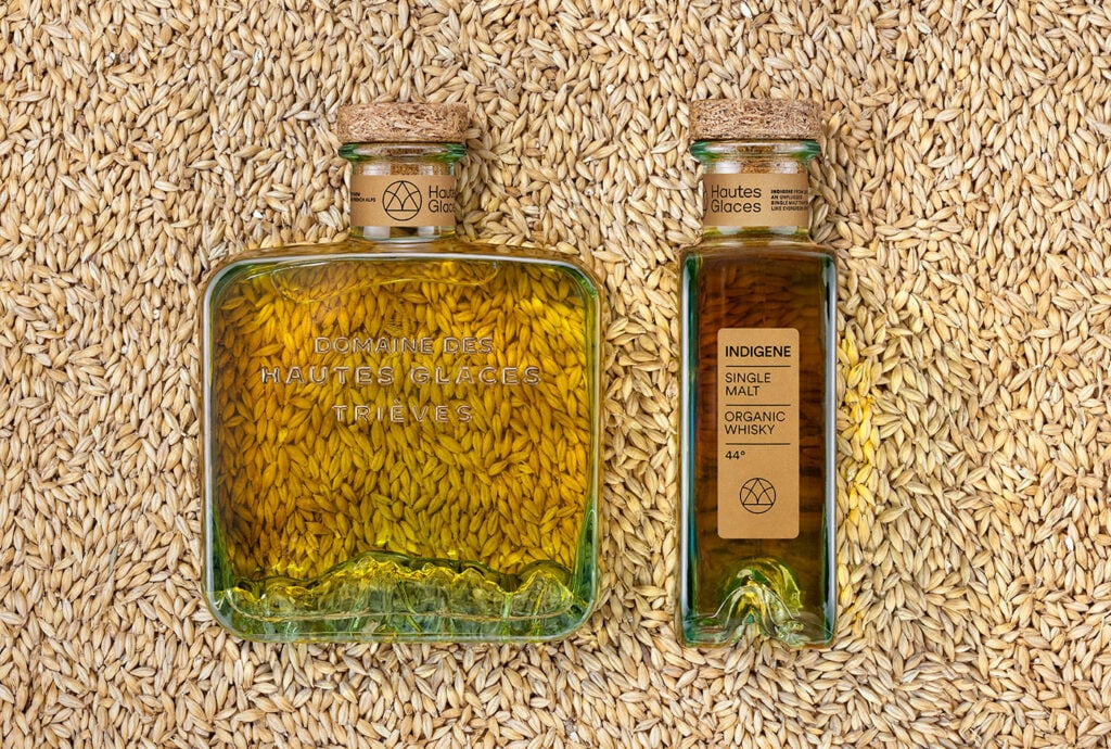 A bottle of Domaine des Hautes Glaces Indigene Organic Whisky against a backdrop of grain