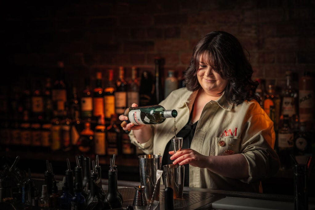 Laurie Howells, head bartender at Archive & Myth, pouring a drink at the bar