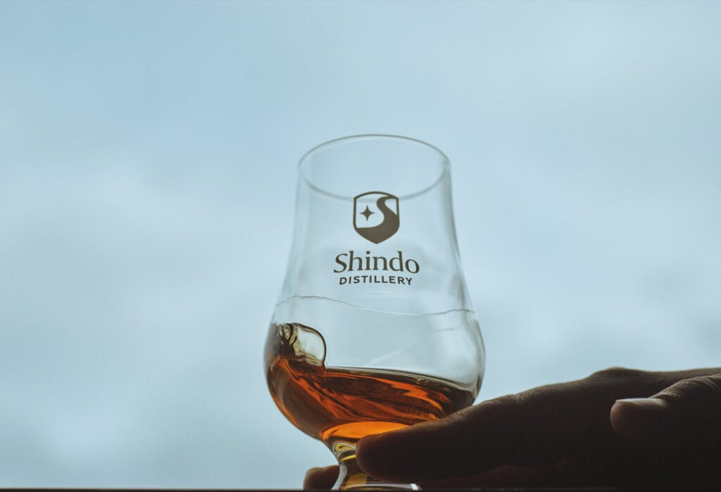 A Glencairn glass marked with Shindo Distillery's logo and filled with whisky
