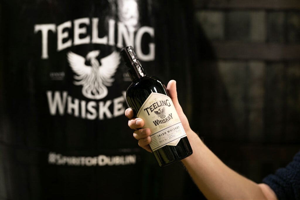 A bottle of Teeling Small Batch held up by a person at the distillery