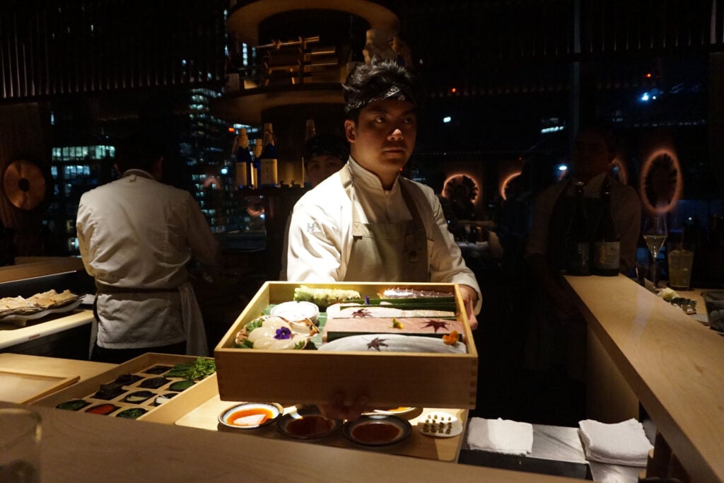 A chef holds a box of smouldering charcoal at Omakase Restaurant for International Whisky Day