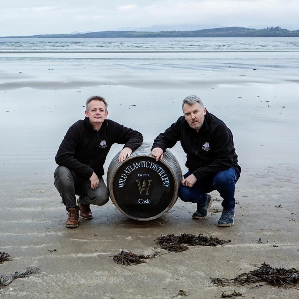 The founders of the Wild Atlantic Distillery with a barrel of whiskey on the beach