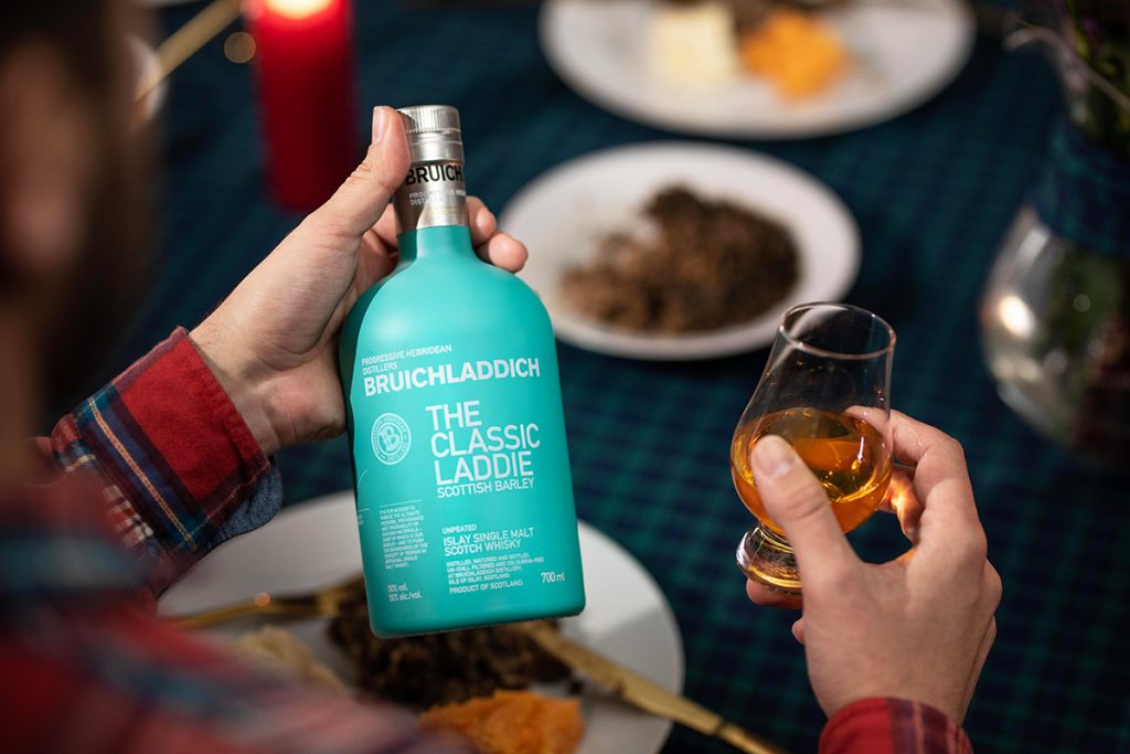 A bottle of the Bruichladdich The Classic Laddie being enjoyed at a Burns Night supper with haggis and tartan decorations