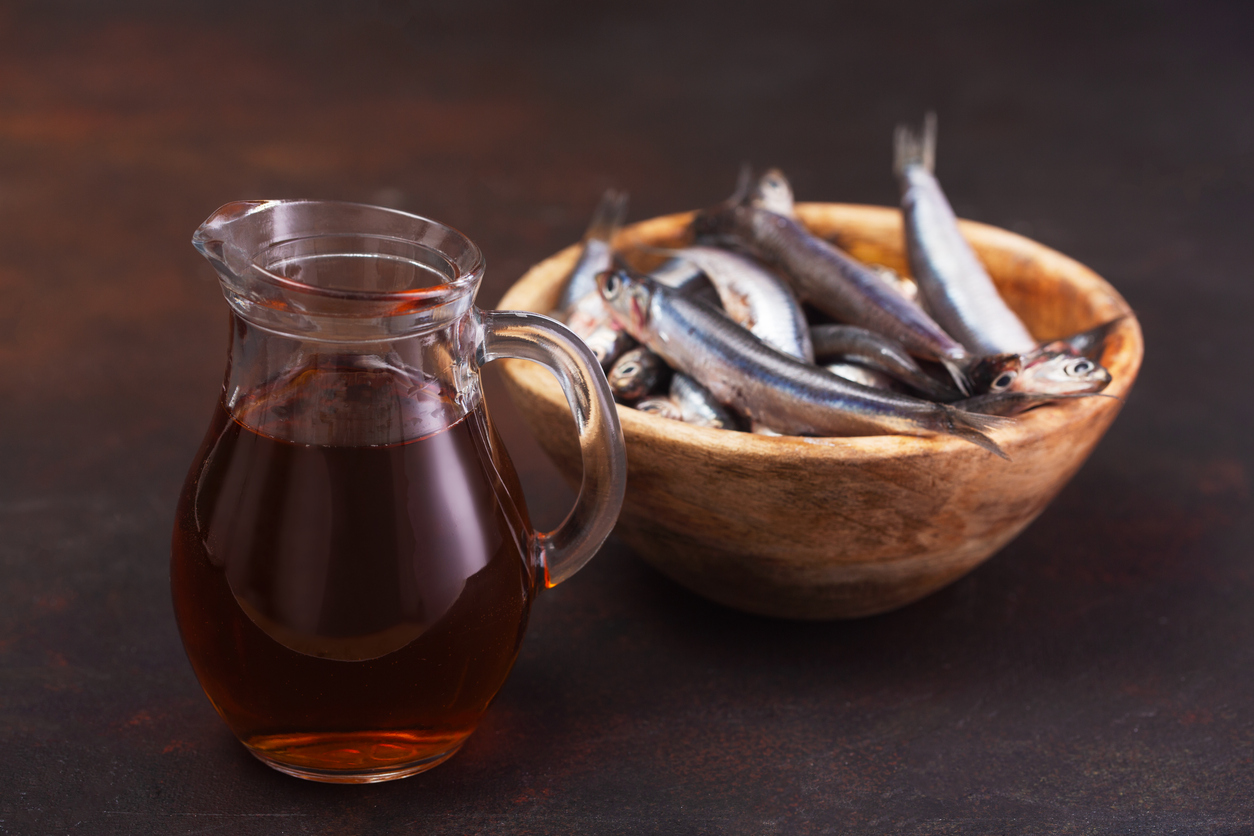 A jug of garum with a bowl of anchovies in the background