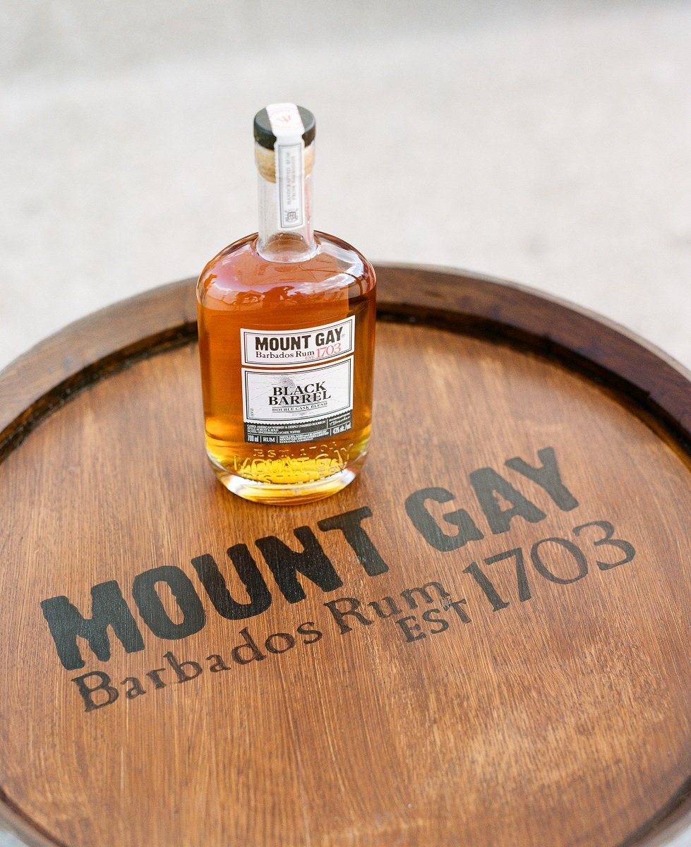A bottle of Mount Gay rum on a wooden barrel