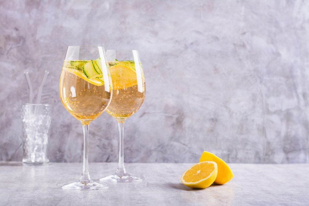 Summer spritz cocktail with champagne, cucumber, lemon and mint in wine glasses on the table