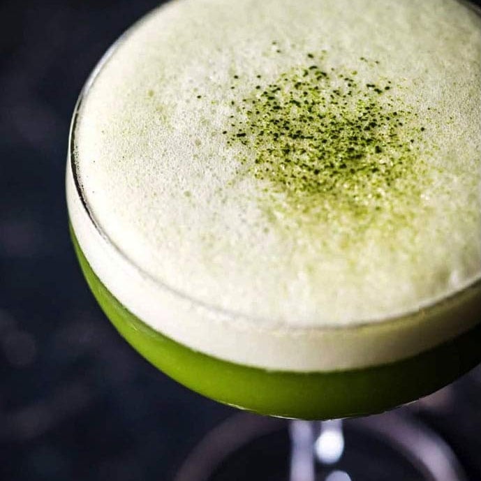 A green sour-style matcha cocktail with foam