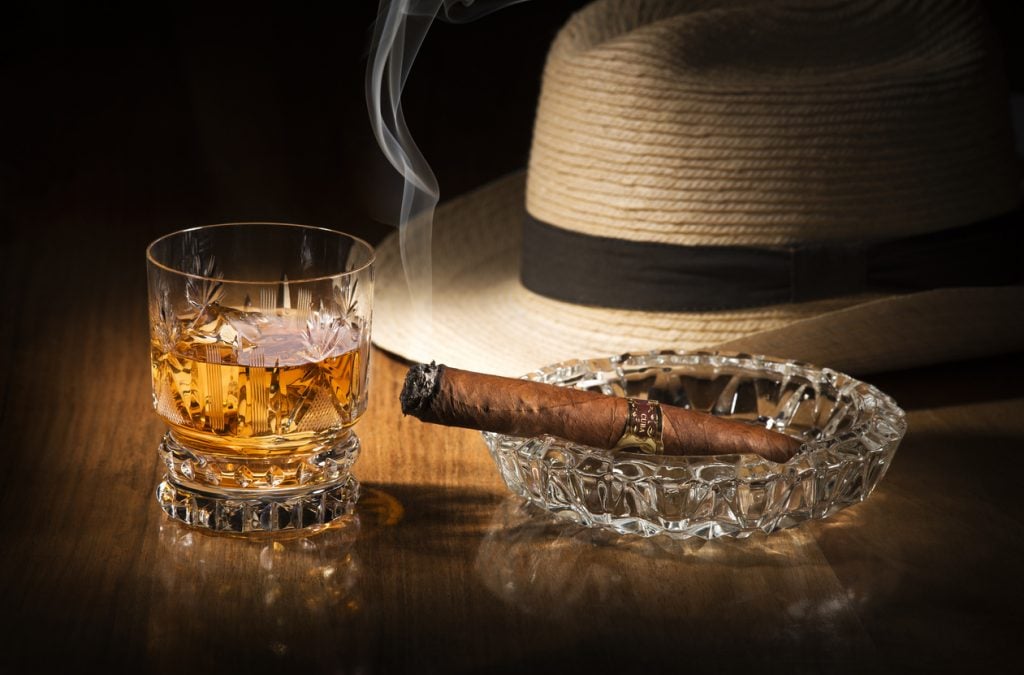 Cuban style hat, rum, and cigar close up