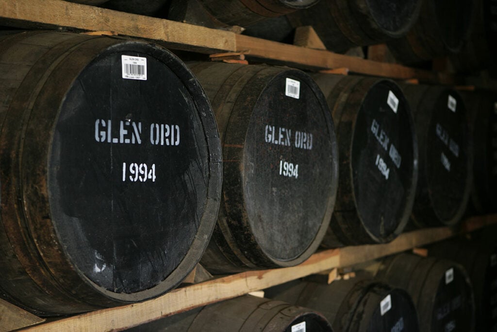 Barrels of malt whisky on a rack in a warehouse at the Glen Ord Distillery, marked with the date 1994 and the distillery name.