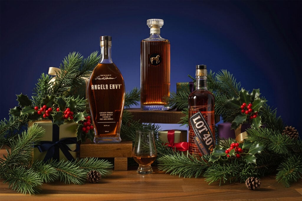 Bourbon bottles pictured among presents and holly for Christmas. Angel's Envy is included, part of The Beginner Christmas Whisky Gift Guide at Master of Malt