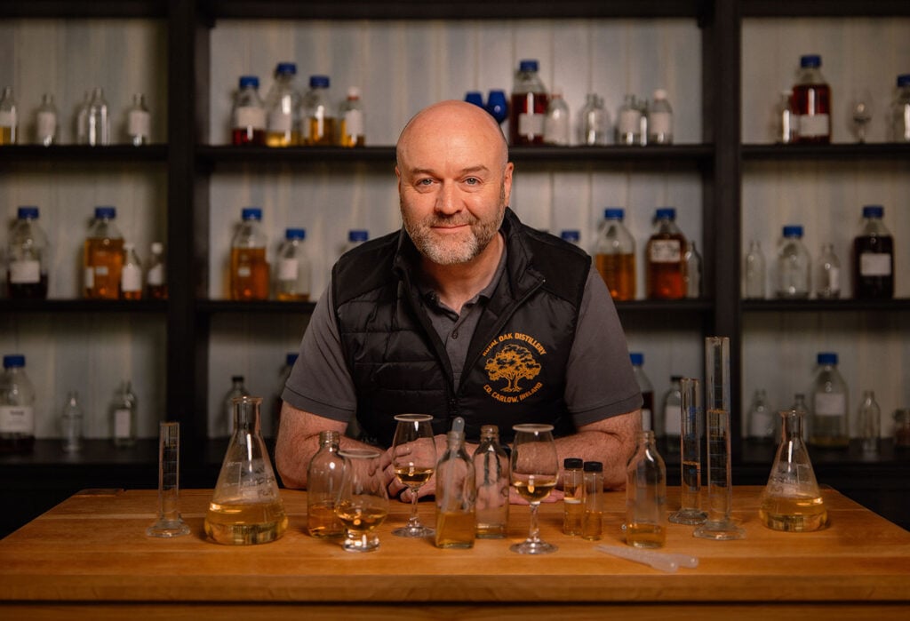 The Busker master blender David Elder at a desk surrounded by whiskey