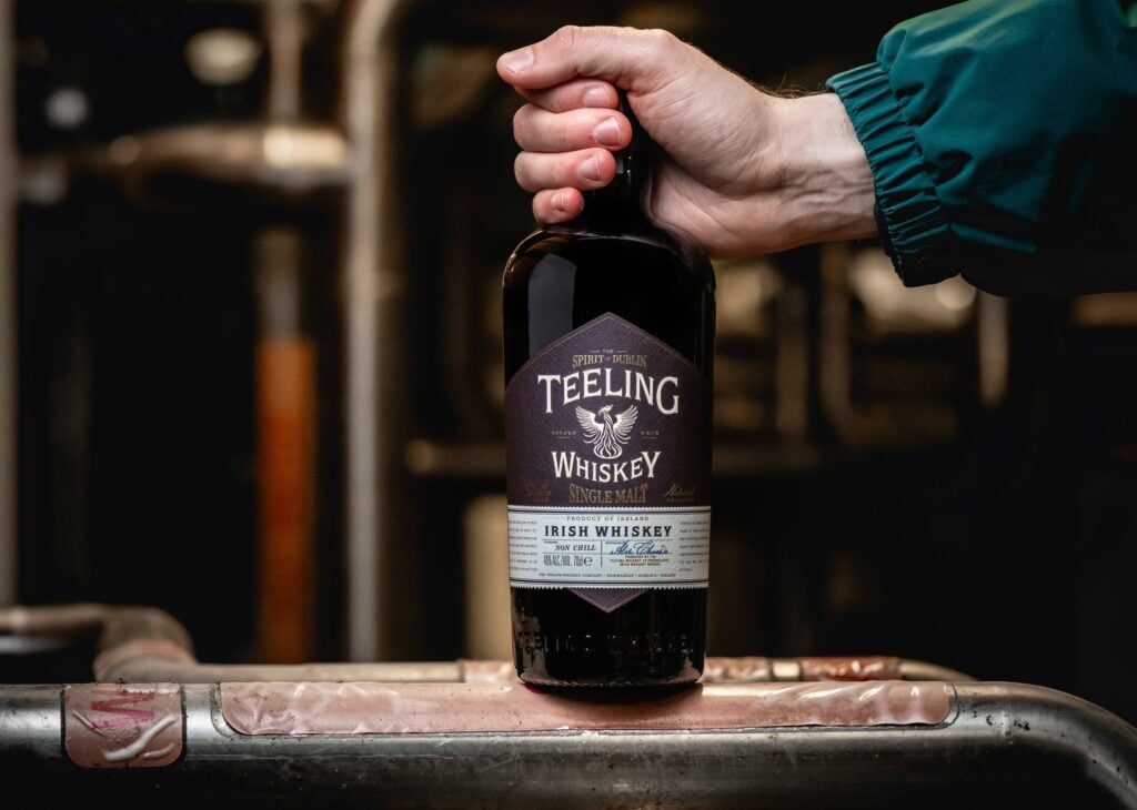 A bottle of Teeling whiskey at the distillery being held by a distillery worker