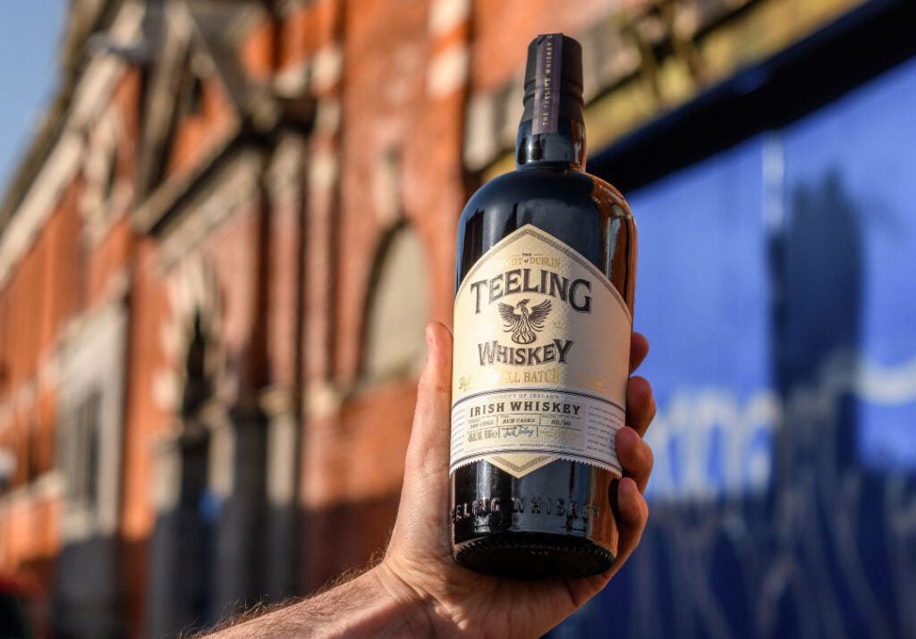 A bottle of Teeling whiskey being held outside of the distillery