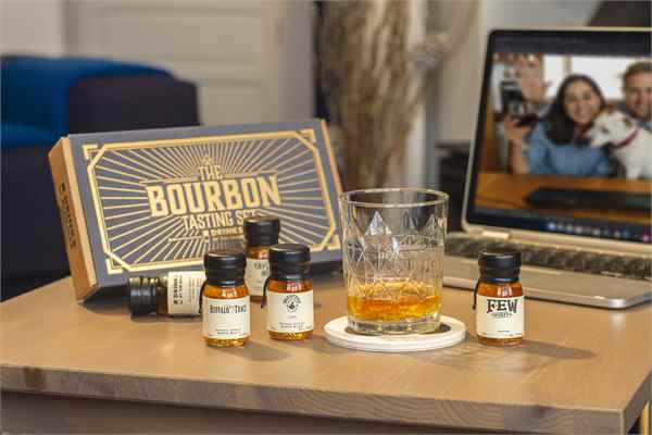 family image on a laptop screen behind a selection of bourbon whisky samples in wax sealed bottles and their bourbon tasting gift box